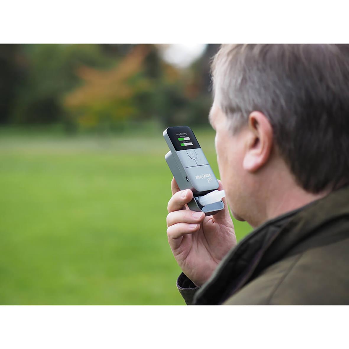 Man använder alkoholmätare Alcosense Pro utomhus i en grön parkmiljö