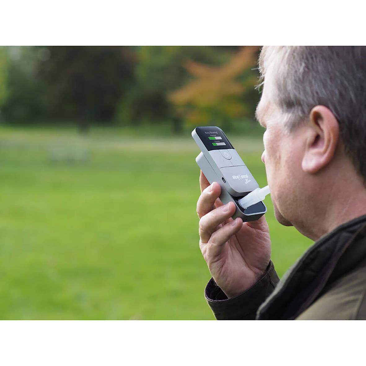 Man använder alkoholmätare Alcosense Ultra utomhus i en grön park