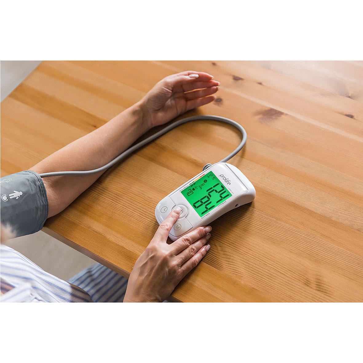 Person som mäter blodtrycket med Prolife Digital PA5 Comfort blodtrycksmätare på ett träbord