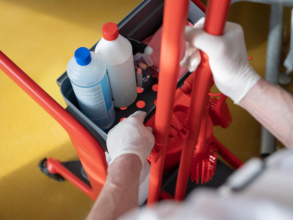 Person i vita handskar placerar rengöringsprodukter i en Vikan Hygo Grön rengöringsstation