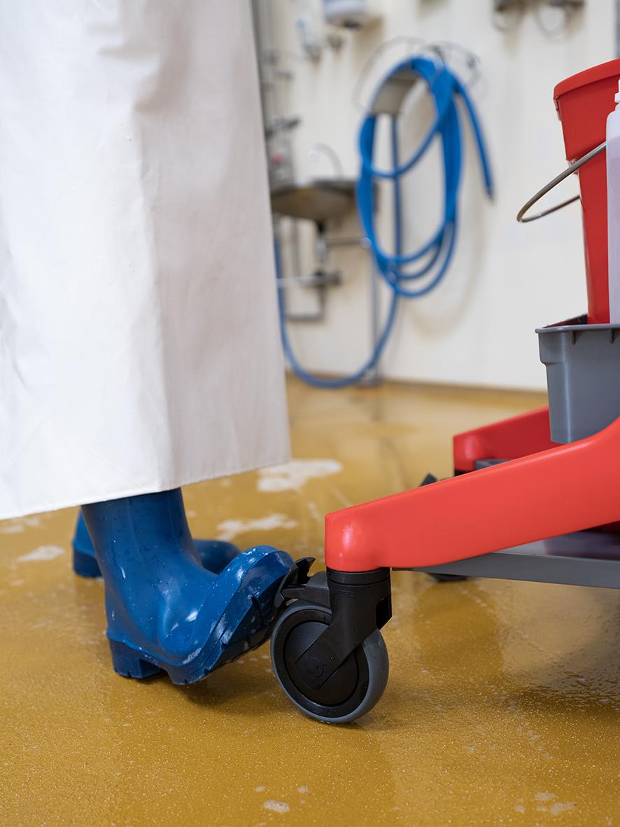 Rengöringsstation med blå vattentillförsel och rullvagn i ett hygieniskt arbetsutrymme