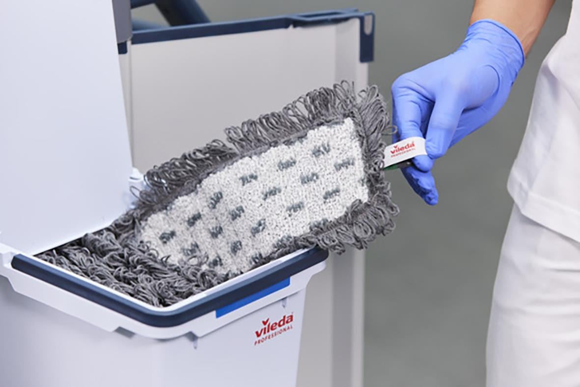 Person som byter mopp i en moppstation med blå handskar