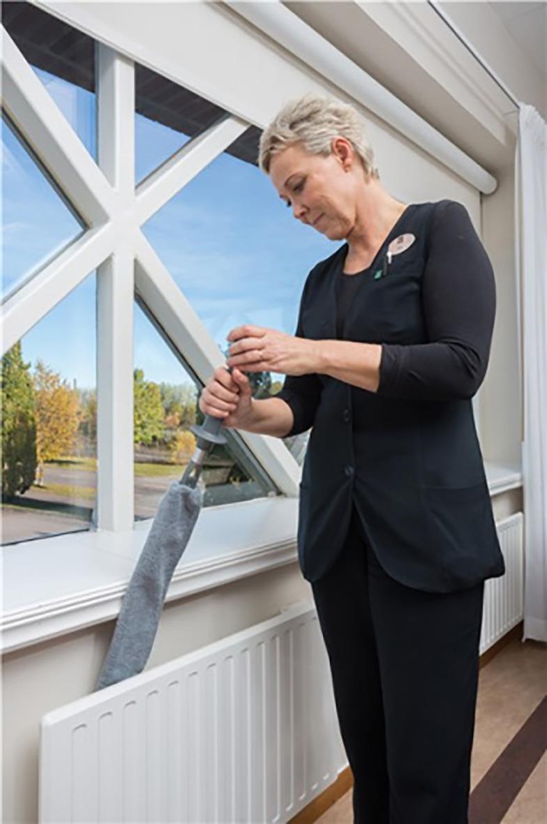 Kvinna använder ett interiörmoppstativ Vikan 81cm för att rengöra ett fönster inomhus