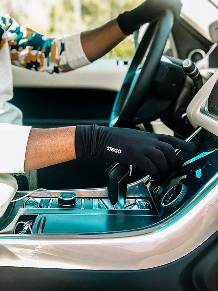 Person använder svart Stogo All-Day Handske i bil, nära växelspaken, utomhusmiljö