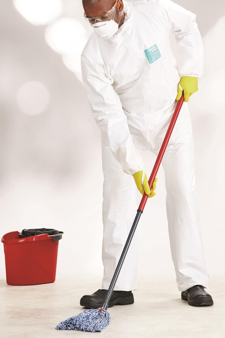 Person i skyddskläder och mask som moppar golvet med en mopp och en röd hink