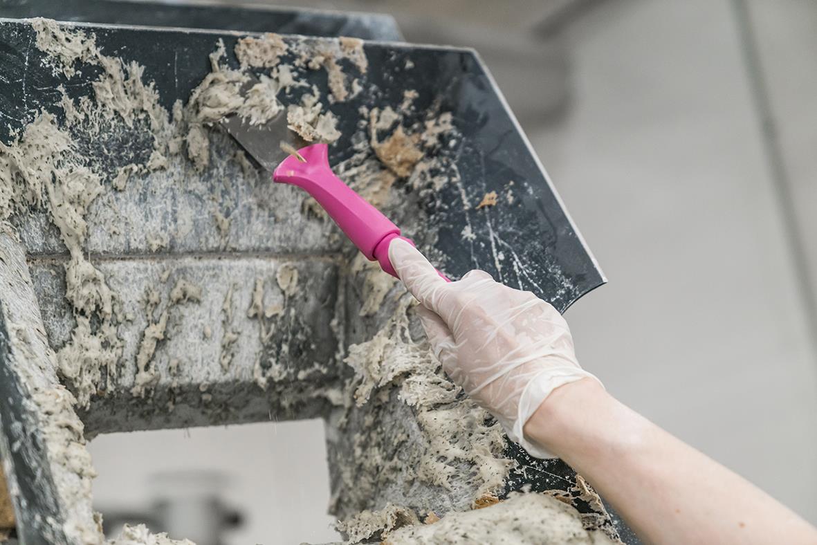 Person använder en rosa handskrapa för att ta bort rost från ett metallhandtag