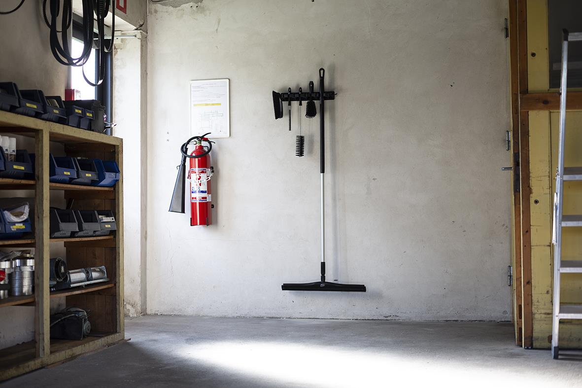 Golvskrapa Vikan Fast Polypropen svart 600mm står mot en vägg i ett garage eller verkstad