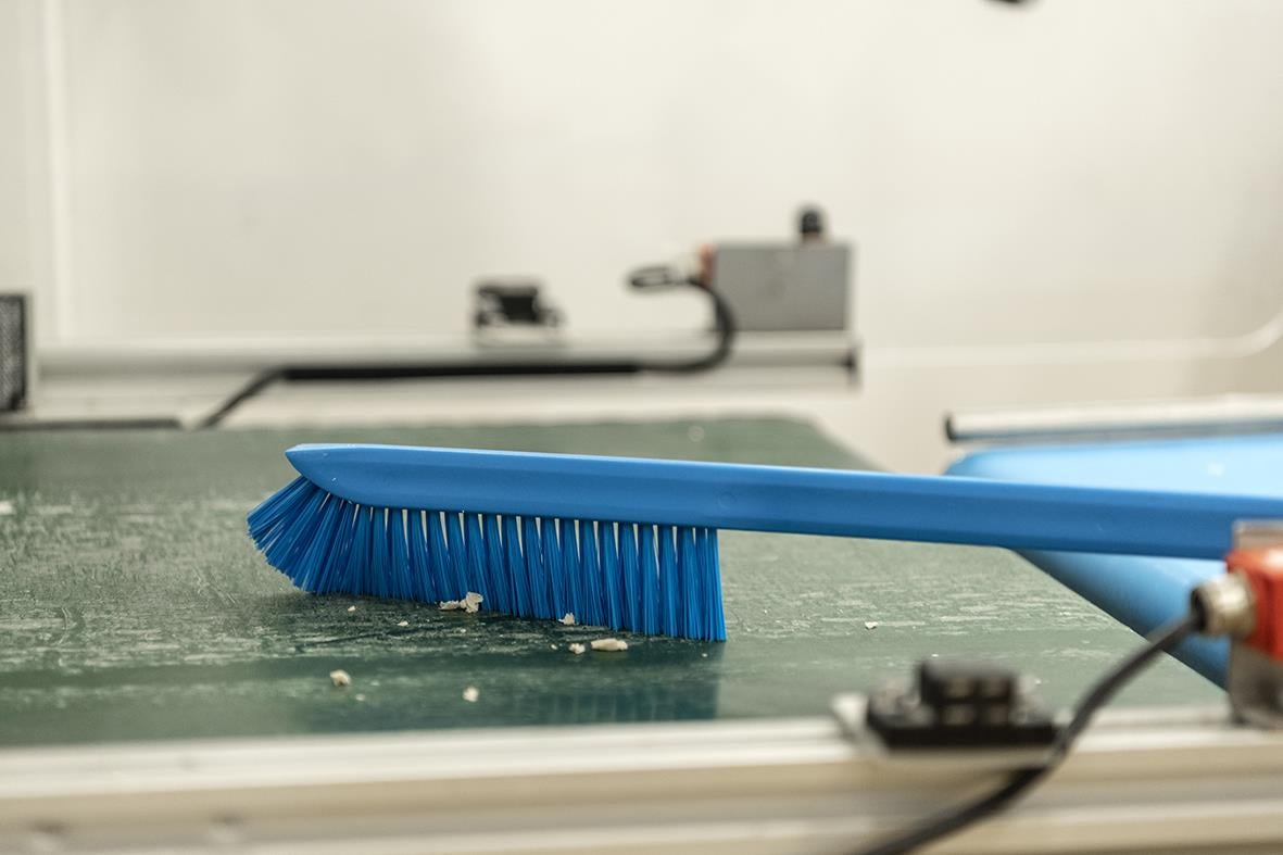 Blå tvättborste med långt skaft på 600mm ligger på en arbetsbänk