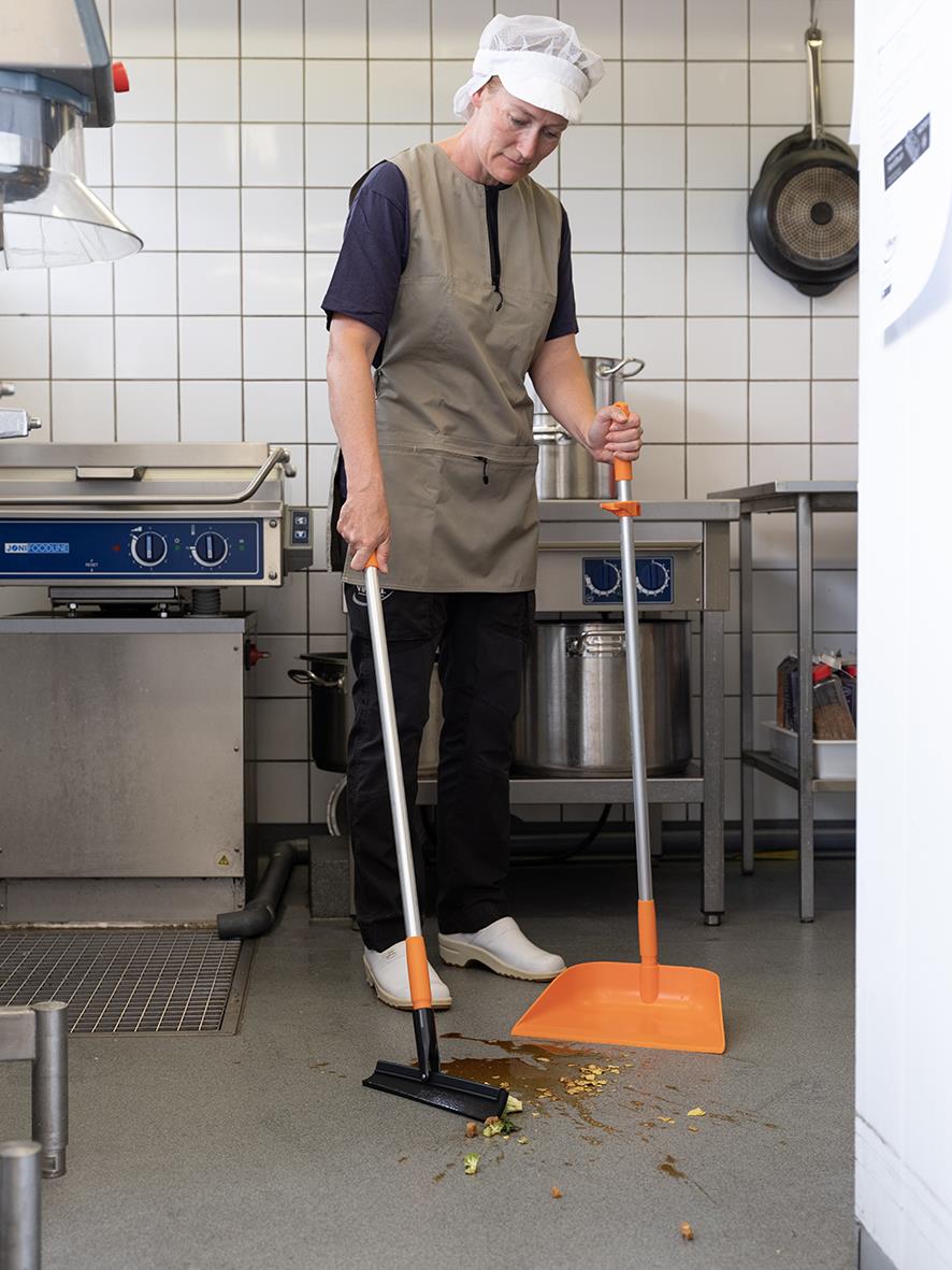 Person som använder en golvskrapa Vikan Rörlig Led Svart 260mm på ett köksgolv