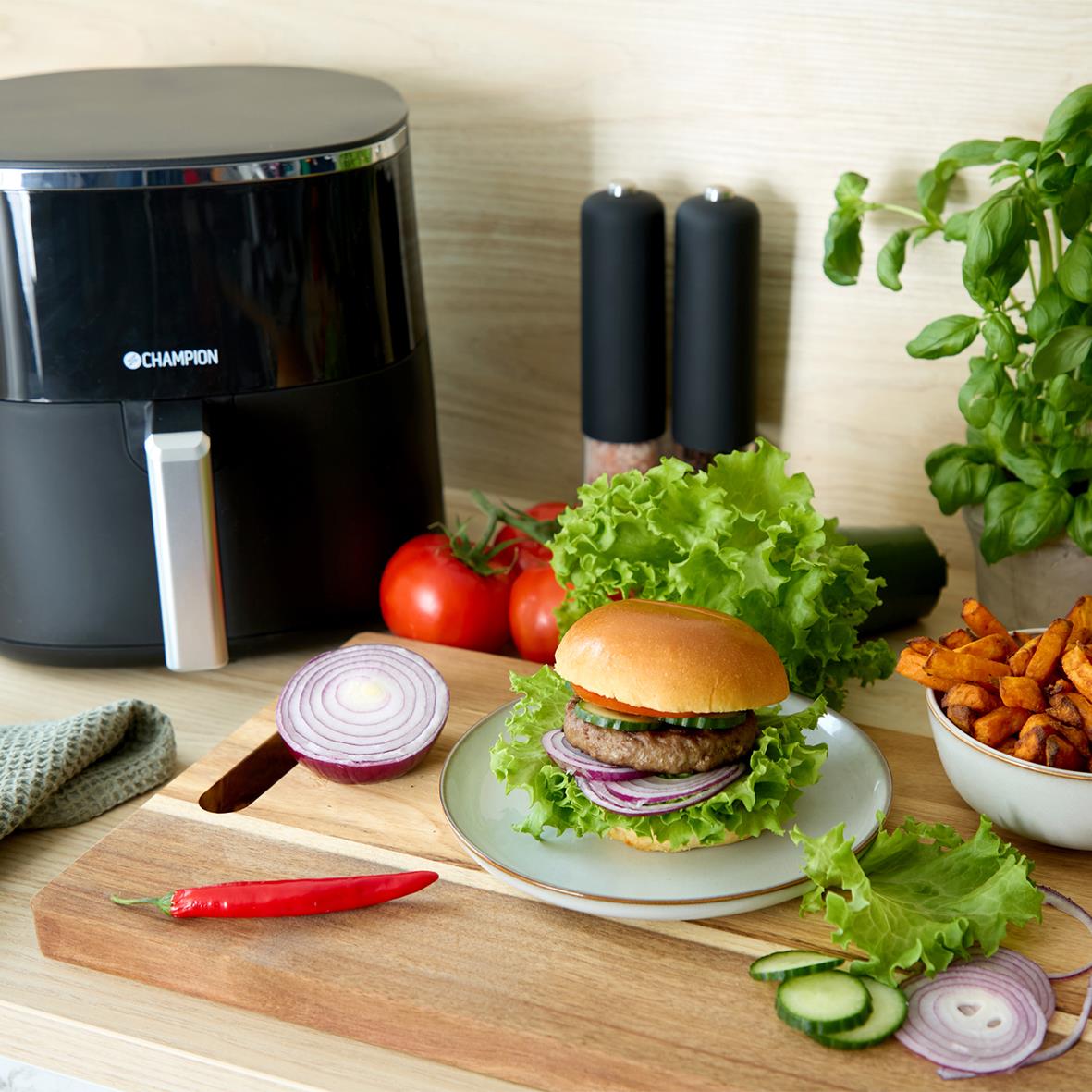 Svart Champion airfryer på köksbänk med hamburgare, pommes frites och grönsaker