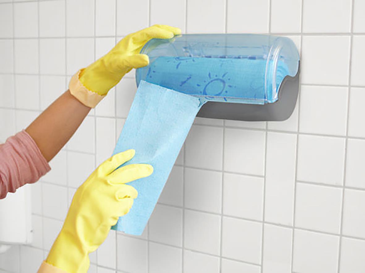 Person med gula handskar använder en blå svampduk Wettex Quick'n Dry på rulle för städning