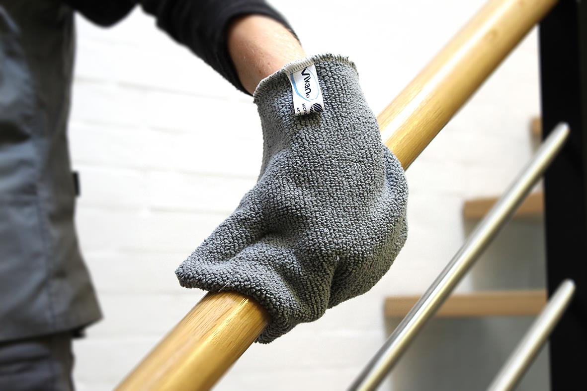 Person som använder en grön microfiber rengöringsvante från Vikan på ett trähandtag