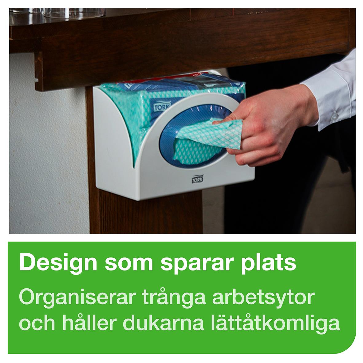 Dispenser Tork W8 liten vit för papper, monterad på vägg, under ett träbord, med text om design och funktion