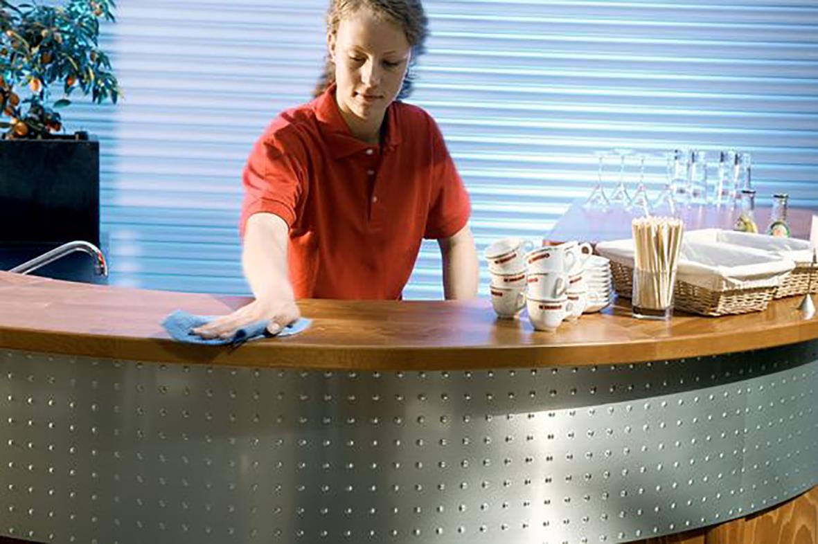 Person som torkar en bar yta med en röd och blå svampduk