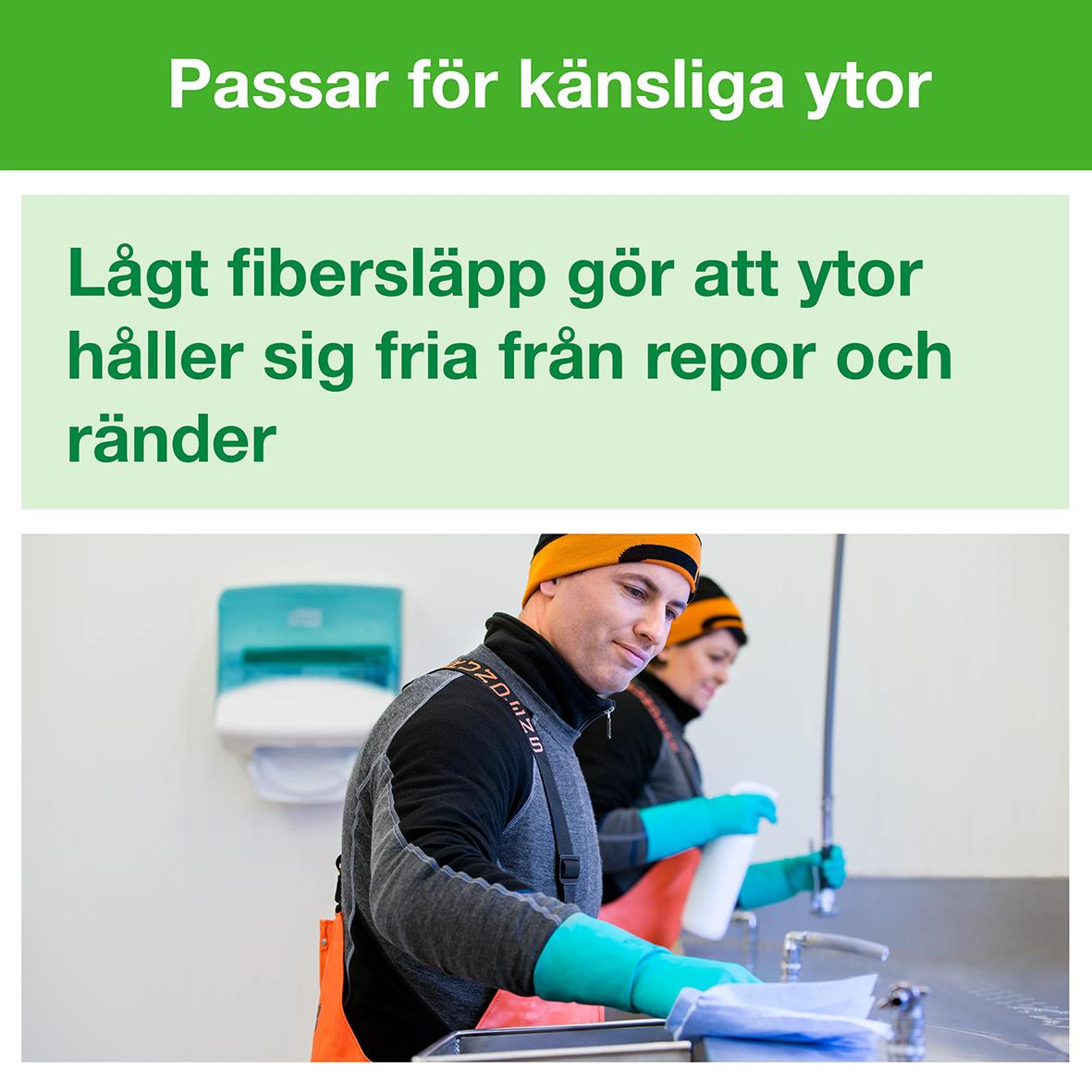 Två personer i skyddskläder och handskar rengör en yta med en rengöringsduk i ett inomhusmiljö