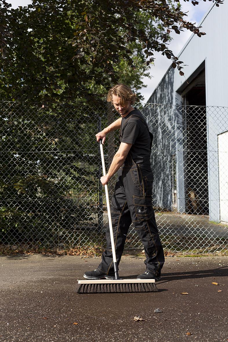 Person med träskaft Vikan Gängad 155cm sopar utomhus framför stängsel och byggnad