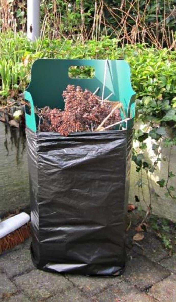 Sopsäcksställ Pack-Bag för 120 liter, röd, 119x79cm, visar en svart sopsäck med ett handtag och en grön bakgrund