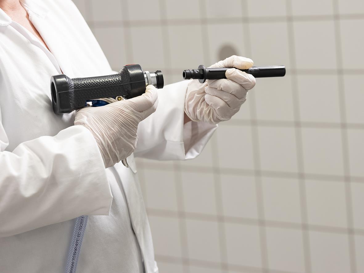 Person håller ett munstycke Vikan av stål och plast 1/2 tum i en laboratoriemiljö