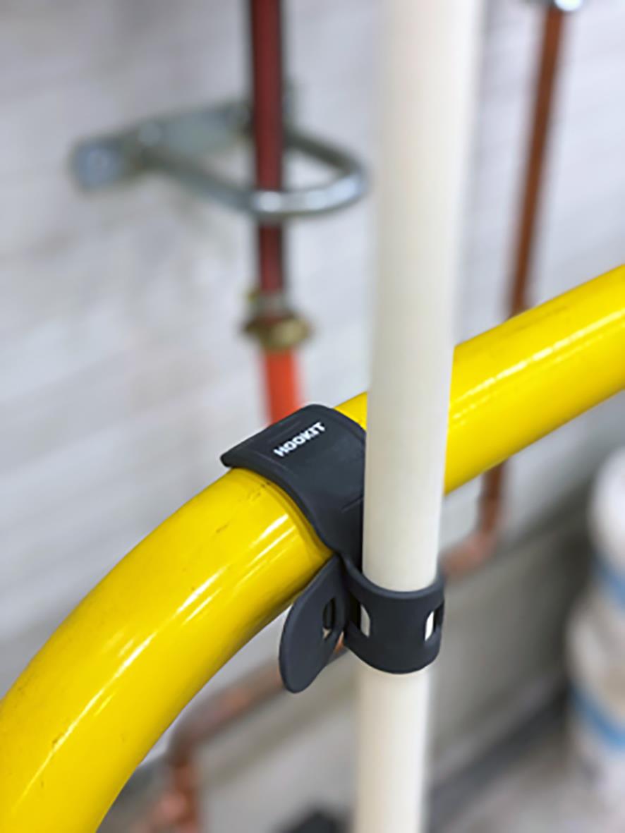 Krok Hookit Pro klämma som håller en vit stång mot en gul rörledning