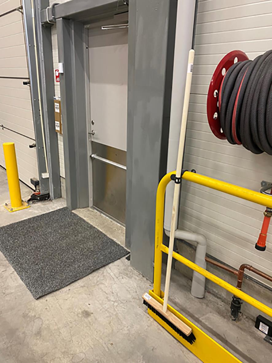 Industriell dörr med krok och skyddsräcke i en lager- eller verkstadsmiljö