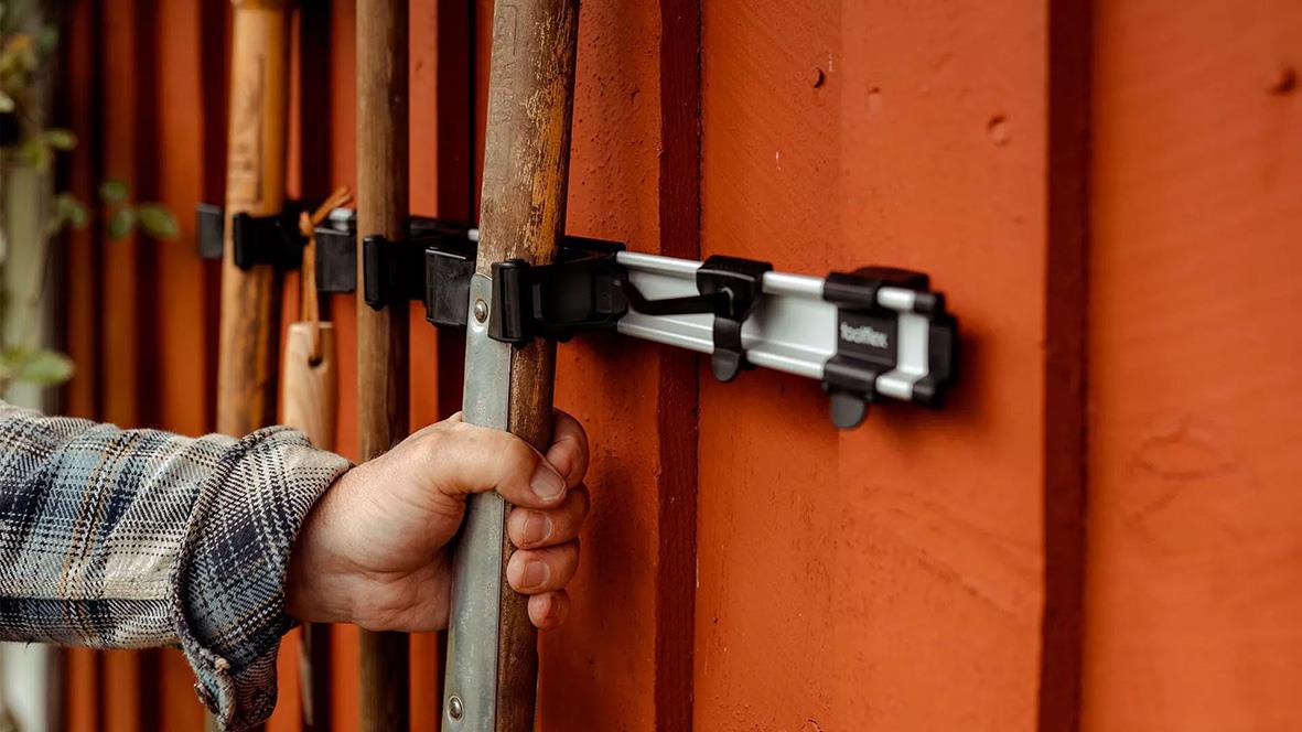 Person som justerar en krok Toolflex till skena på en trävägg