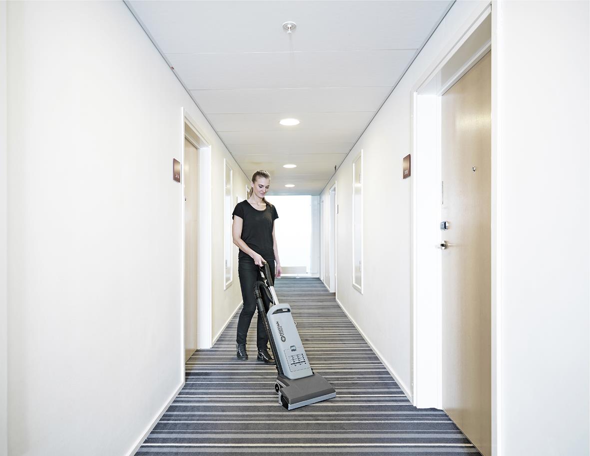 Person som städar en korridor med Nilfisk VU500 15 tum borstvalsdammsugare