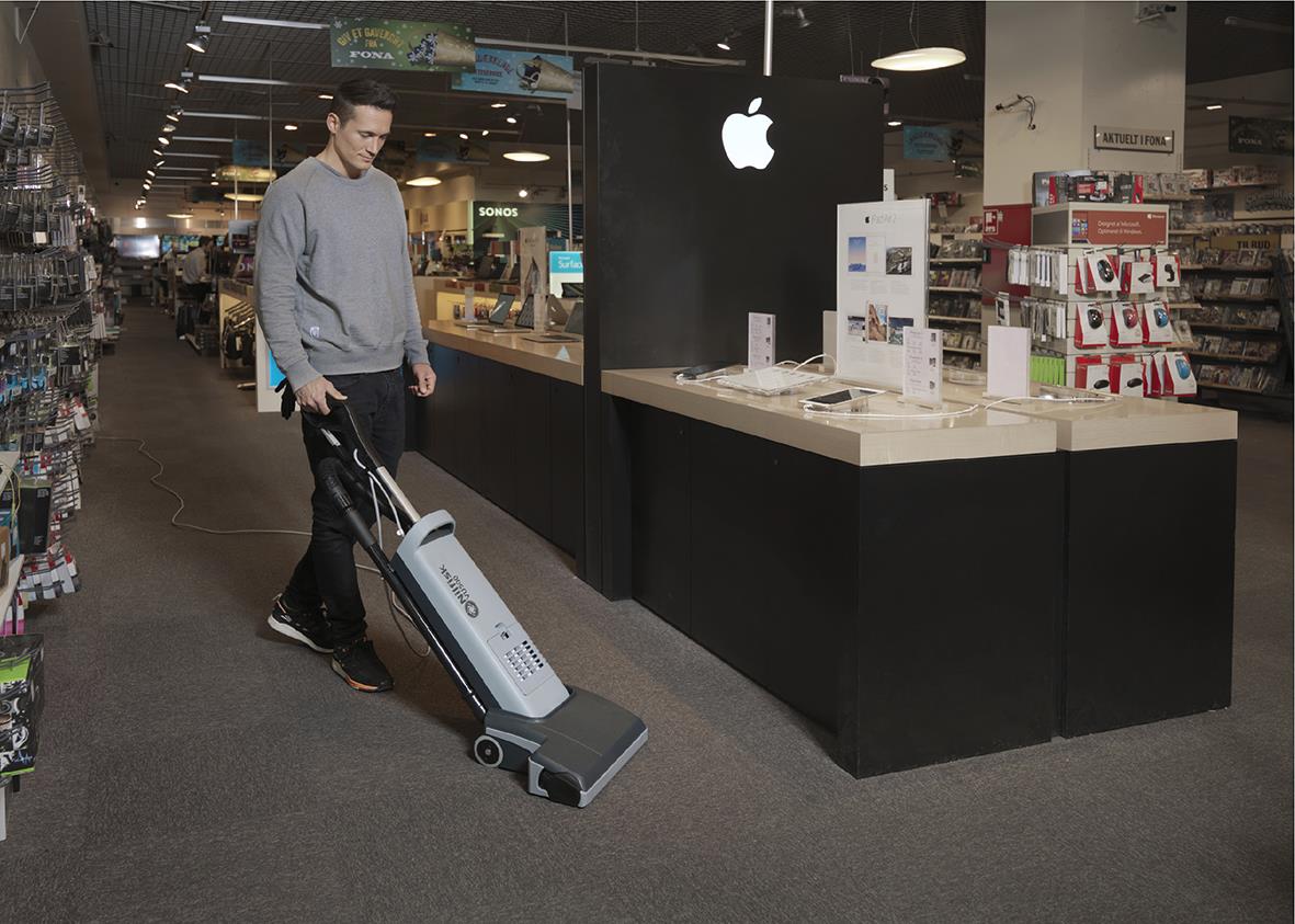 Man använder Nilfisk VU500 borstvalsdammsugare i en elektronikbutik