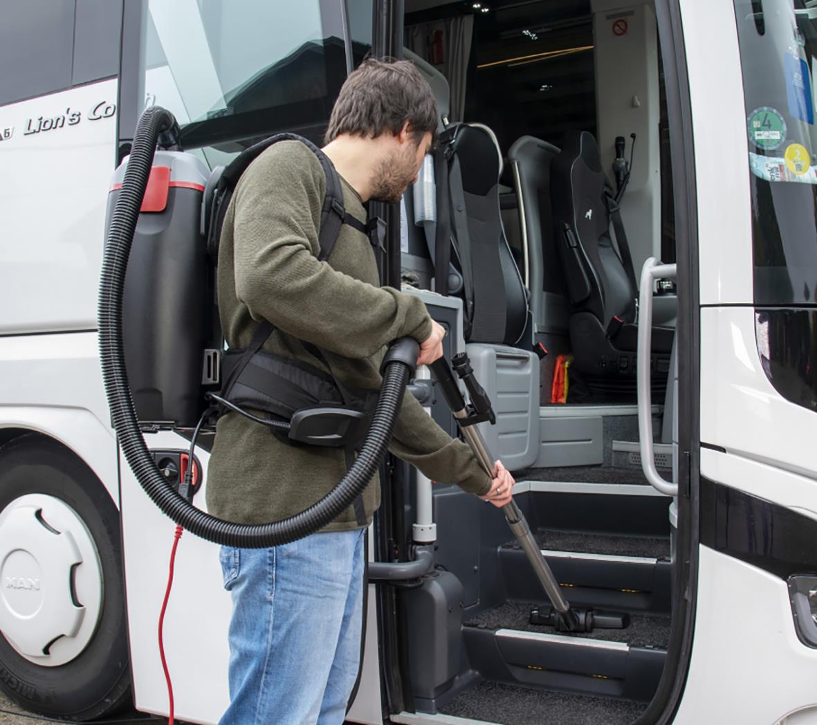 Man använder en ryggdammsugare Sprintus BoostiX Batteri Li-Ion för att städa en buss