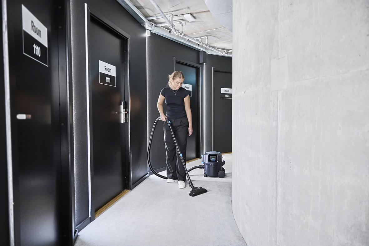Kvinna städar korridor med Nilfisk VP500 R batteridriven dammsugare