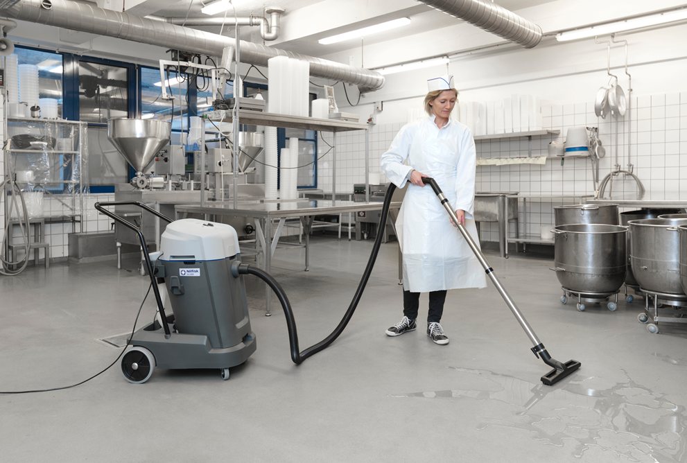 Person använder en Nilfisk VL500 55-2 Ergo våt- och torrsug i ett industriellt kök eller laboratorium