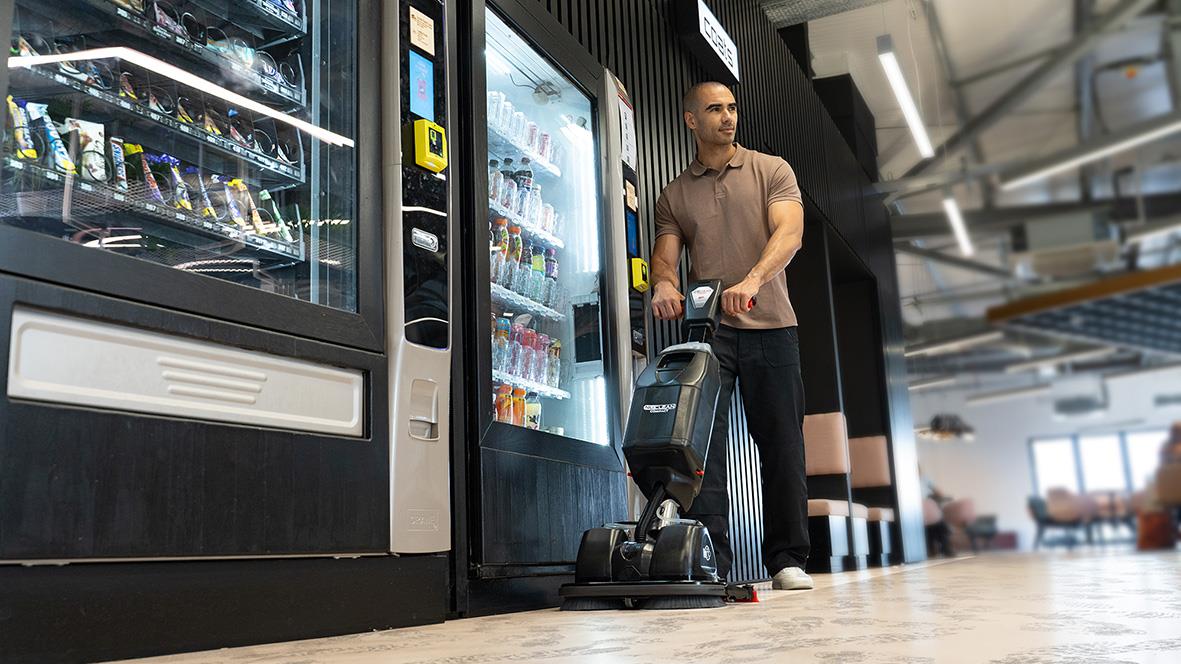 Man med kombiskurmaskin Nu-Mop Flex 2.2I med batteri i en butik eller arbetsmiljö