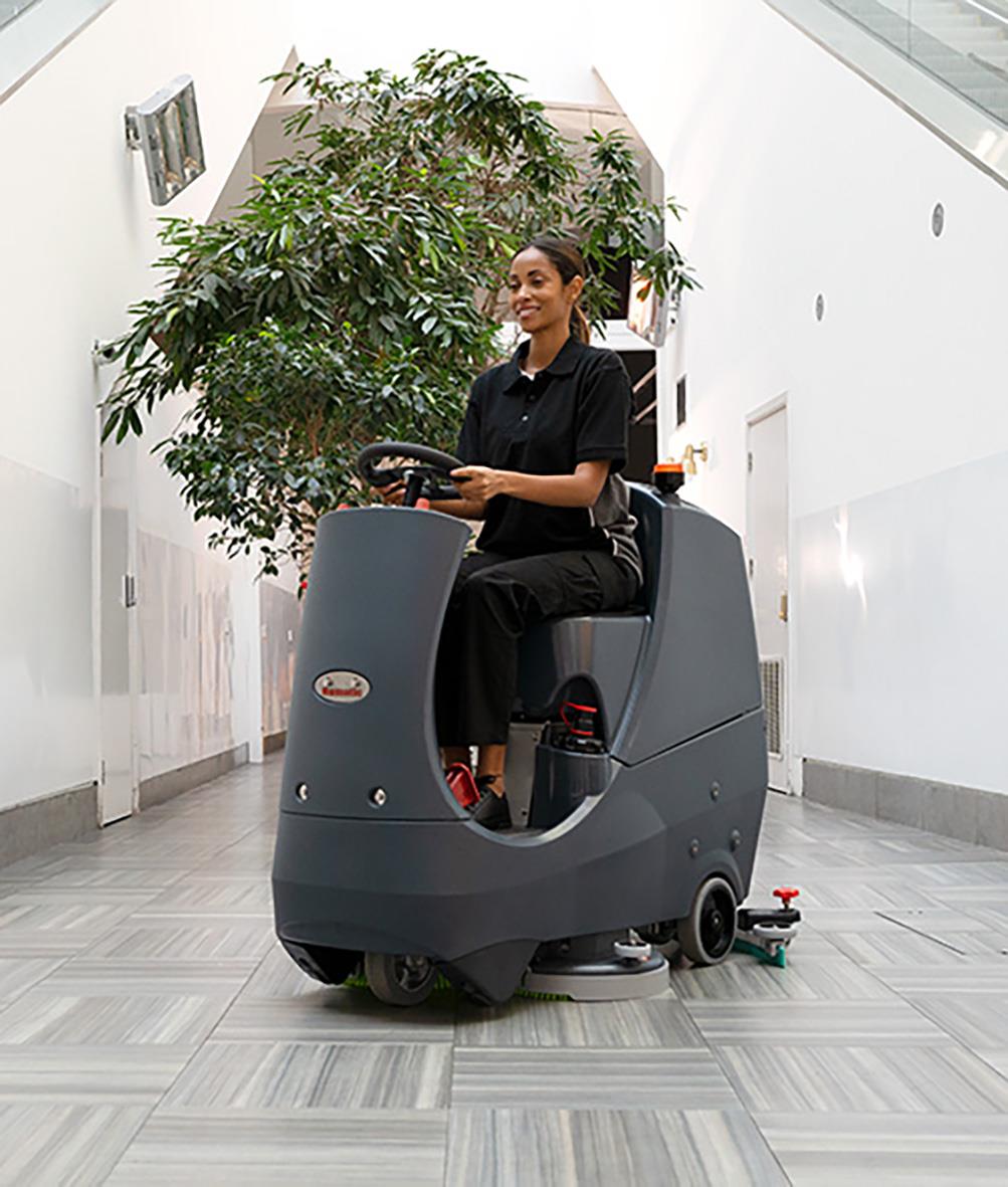 Kvinna som kör en kombimaskin Åkbar Numatic CRL8072 med två batterier och borstar inomhus