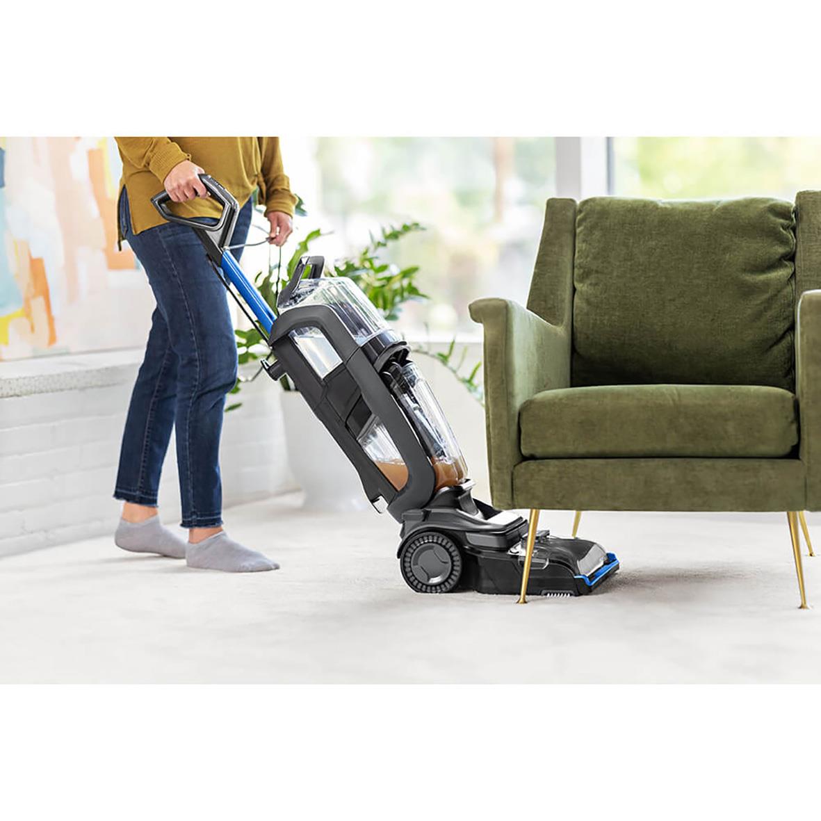 Person som använder Bissell Revolution Hydrosteam mattvättmaskin på en matta i ett vardagsrum