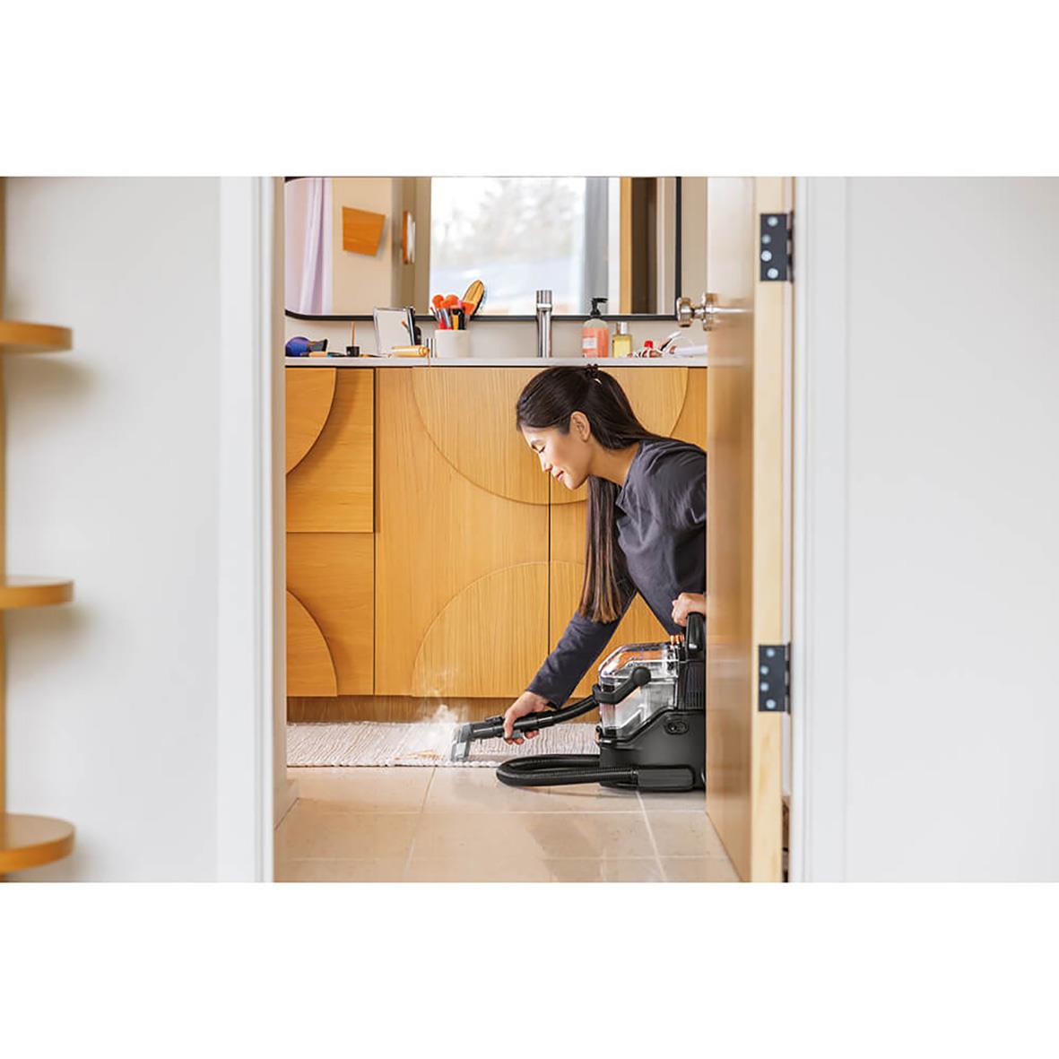 Kvinna rengör matta med Bissell Spotclean Hydrosteam Pro i ett kök