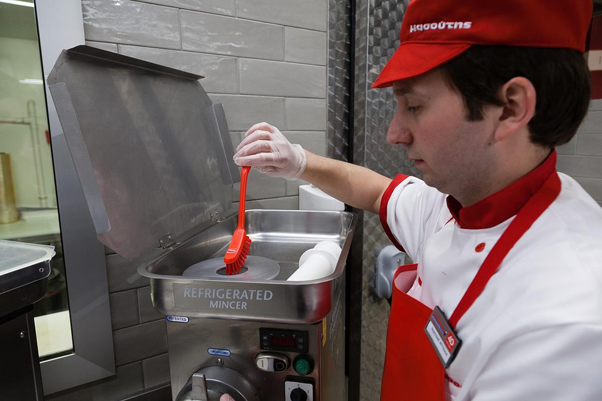 Person som rengör en diskborste i en diskmaskin, arbetsmiljö med kök eller restaurang