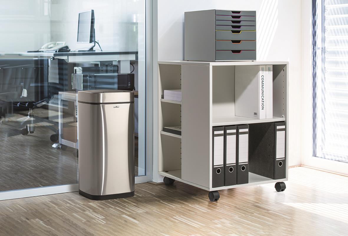 Kontorsutrymme med papperskorg och vit hylla med arkivfiler på hjul