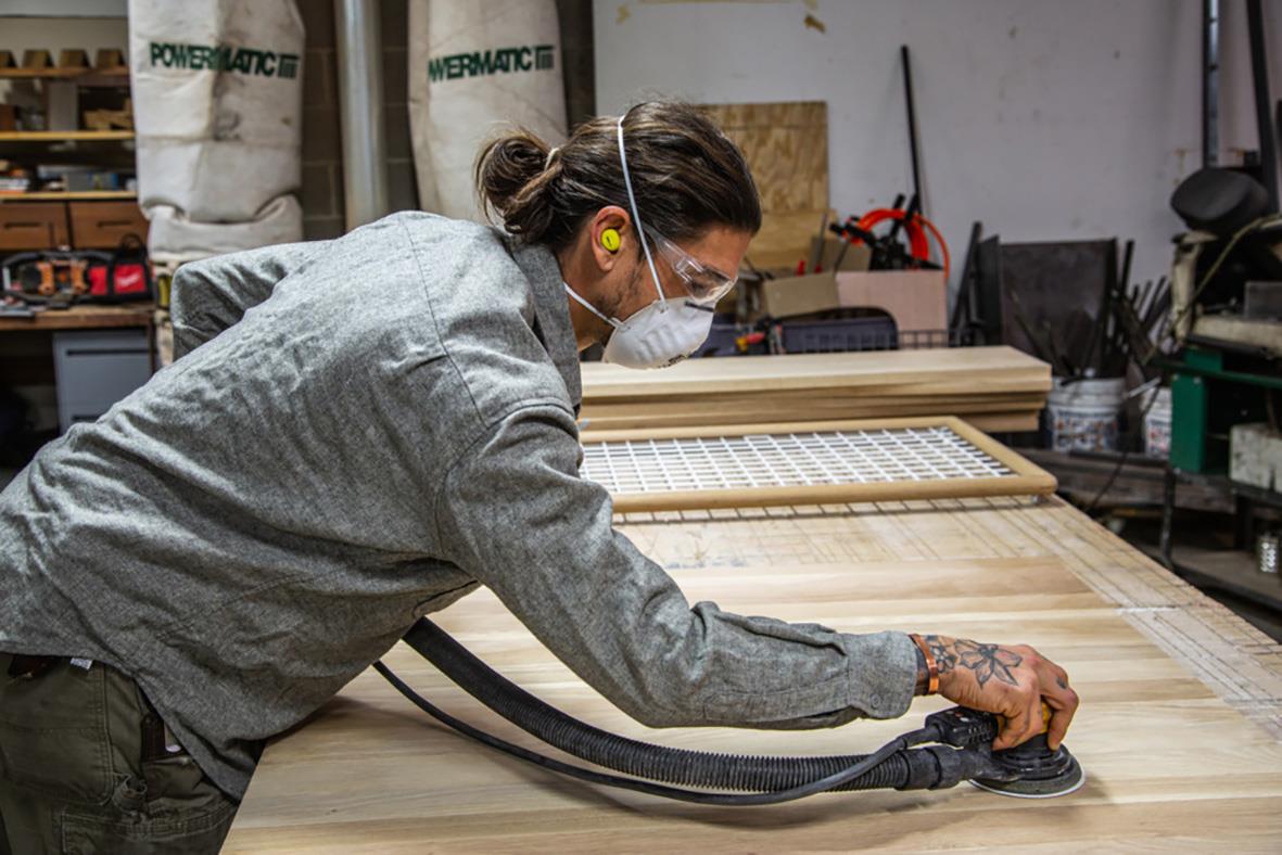 Person som använder Isotunes Free 2.0 BT Industriella hörselproppar i ett verkstadsmiljö