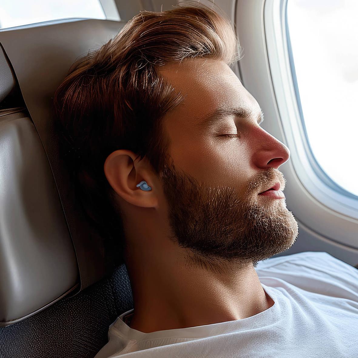 Man med hörselskydd som vilar med ögonen stängda på ett flygplan