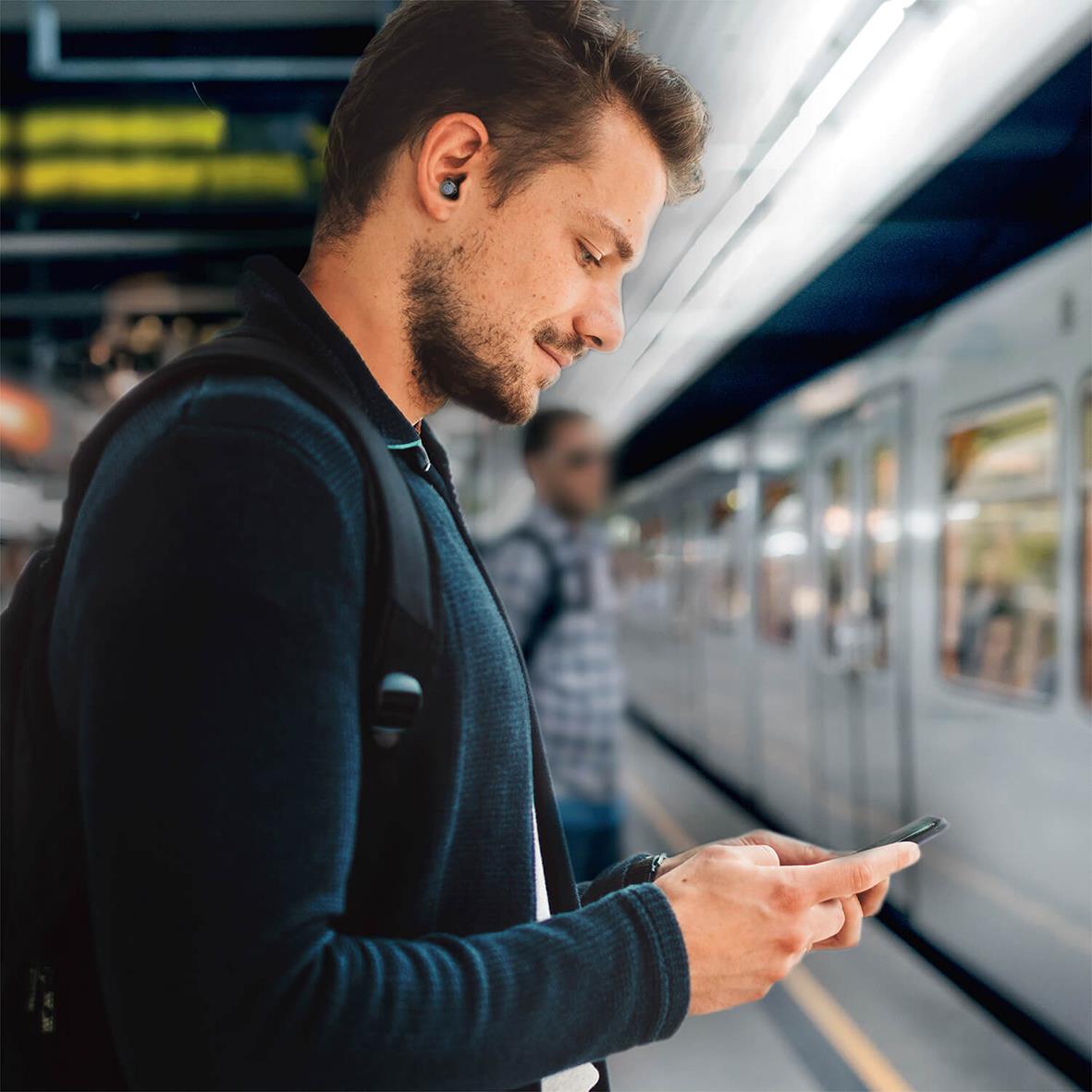 Ung man med hörselskydd Mixx Noise Protection adaptiv justerbar på tunnelbanestation