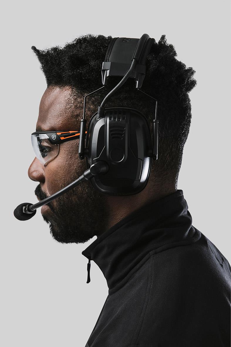 Person med skyddsglasögon och hörselskydd i profil, grå bakgrund