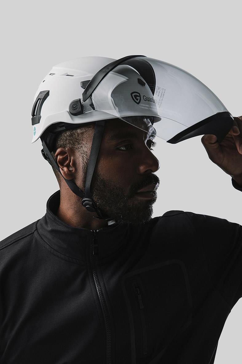 Man i svart jacka justerar en vit skyddshjälm Guardio Armet med visir