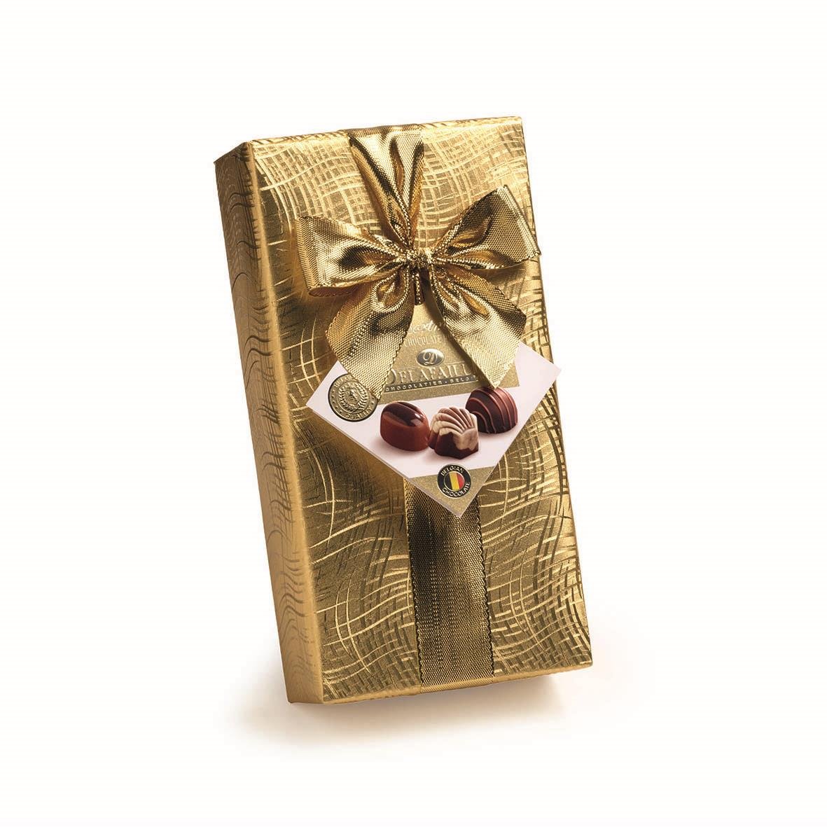 Guldfärgad presentförpackning med chokladpraliner och guldsnörad rosett