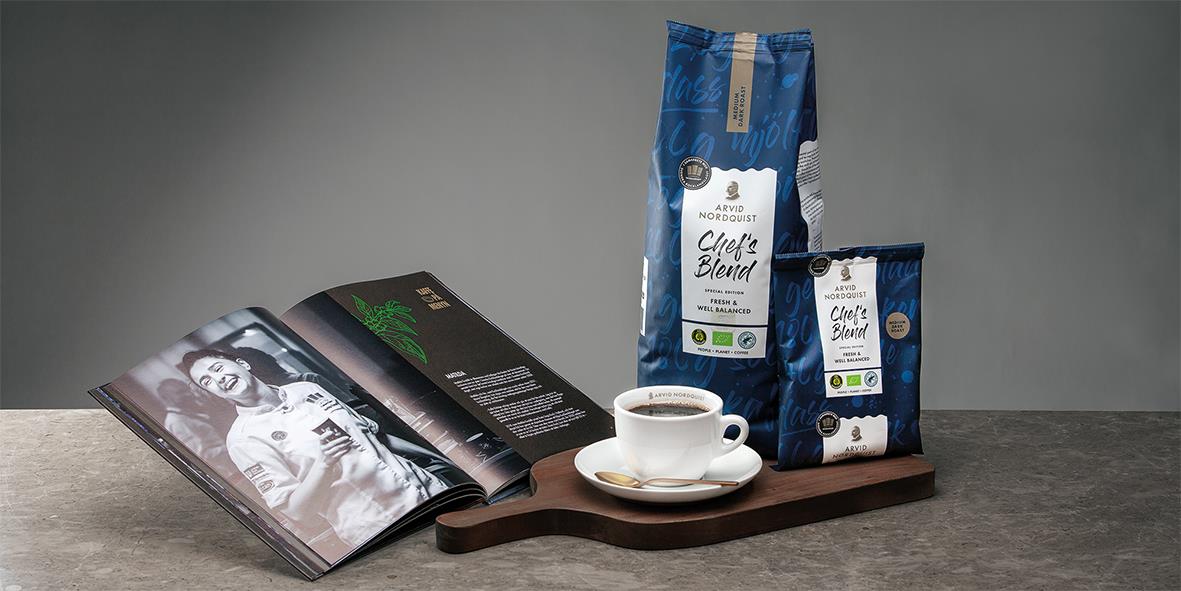 Kaffe Arvid Nordquist Chef's Blend hela bönor 1000g, en kopp kaffe, ett magasin och kaffepaket på en träbricka