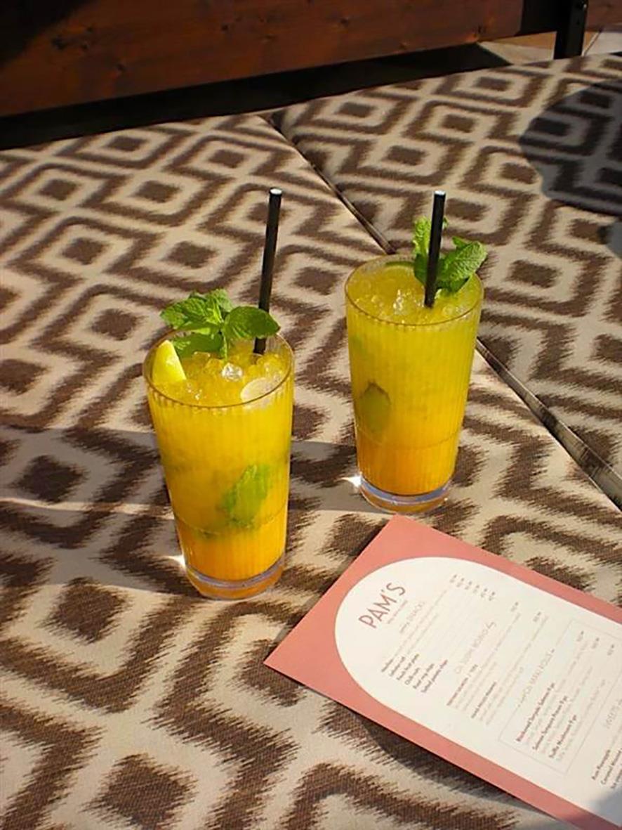 Två stripehöga drinkglas med citron- och myntdekoration på ett mönstrat bord