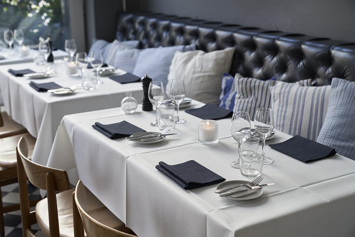 Vitt duktyg med duk Duni Evolin Vit 127x220cm på ett bord för middagsdukning