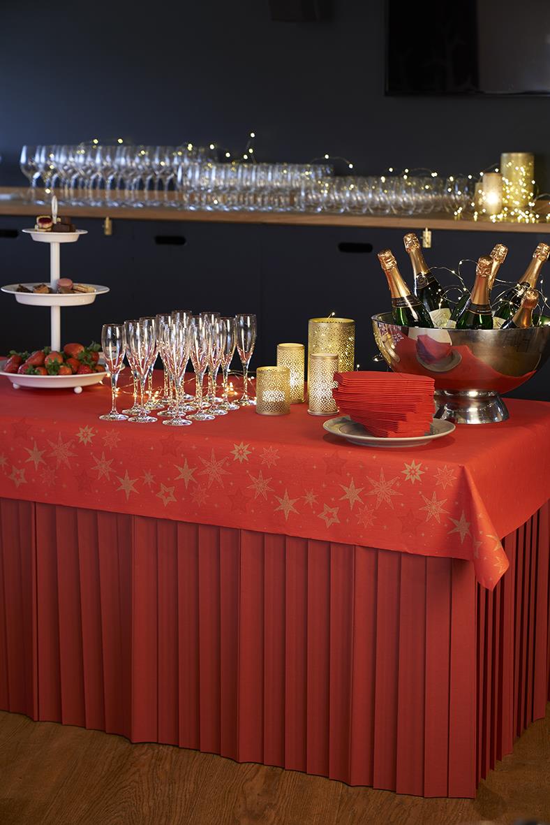 Bord med röd julduk, champagneflaskor, glas, ljuslyktor och snacks, festdekoration för julfest