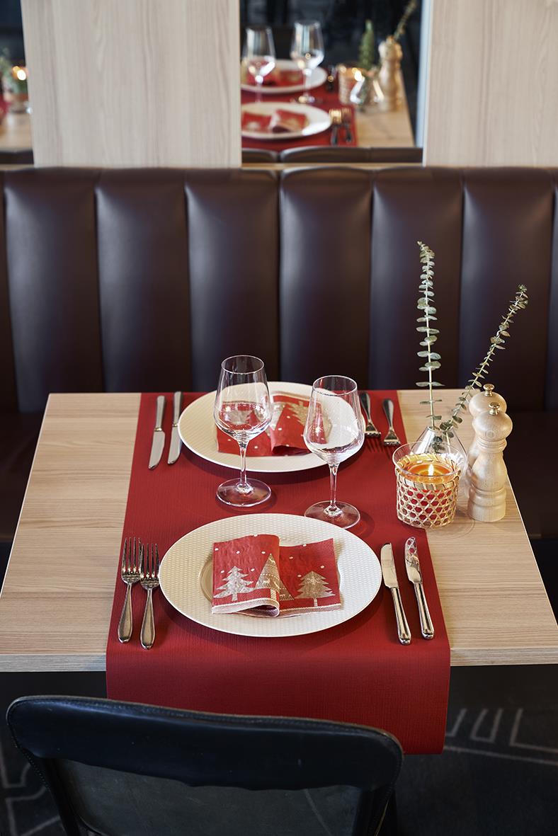 Vacker middagsdukning med röd löpare, vita tallrikar, glas, bestick och dekorationer på ett bord i ett modernt kök eller restaurang.