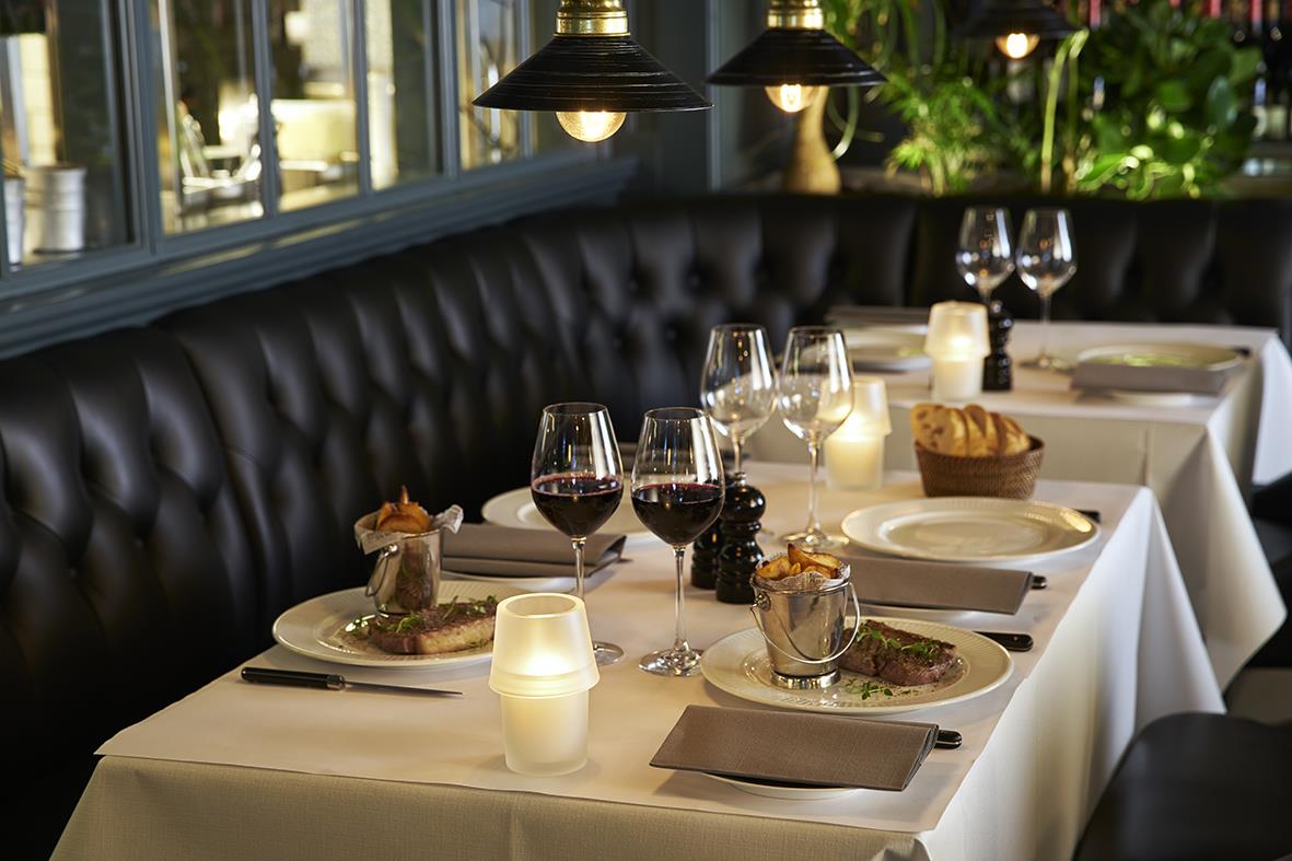 Vitt duk Duni på 70x70cm är elegant placerad på ett dukat bord i en restaurangmiljö