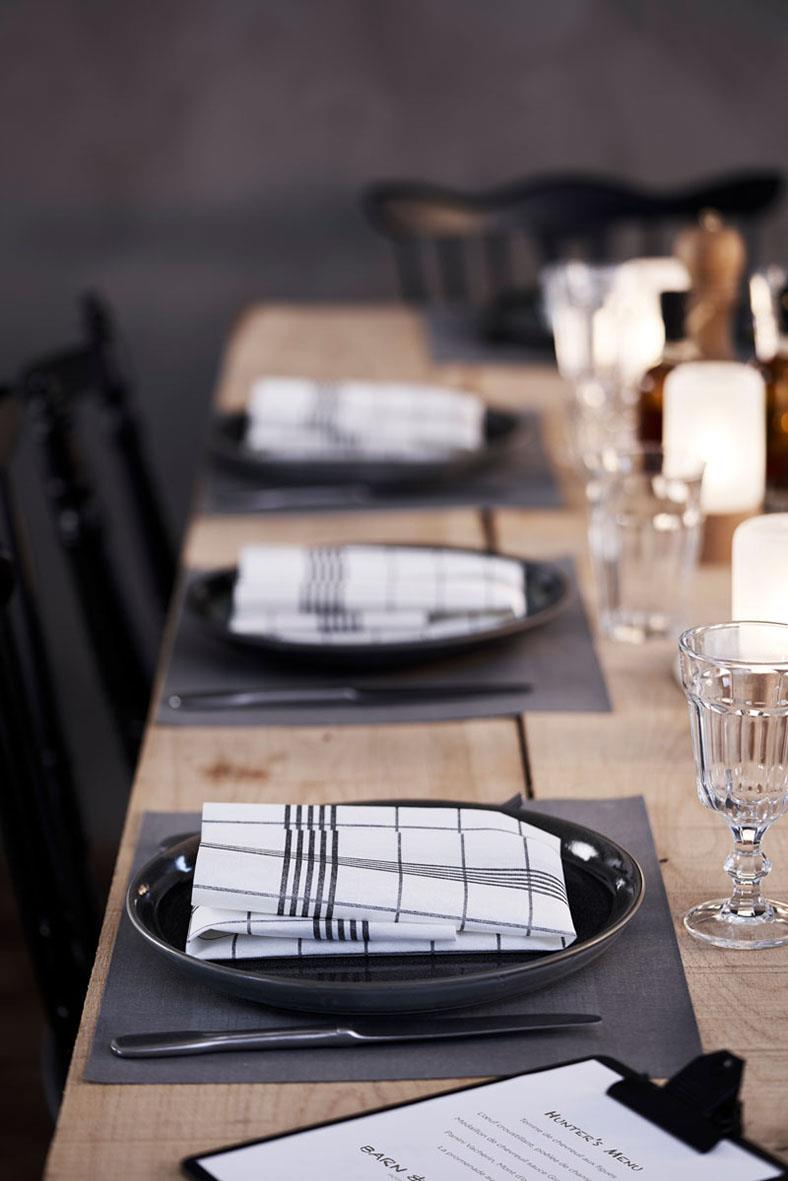 Serveringsfat av Duni BIO Dunicel Linnea i svart på ett bord med tallrikar, bestick och glas