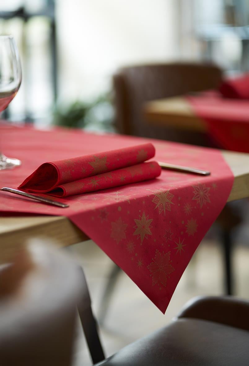 Röd julduk med guldiga snöflingor på ett bord, med bestick och servett